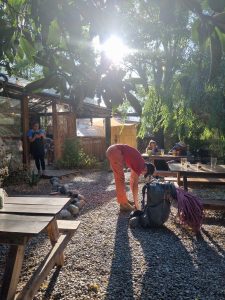 Botas de trekking junto a una mesa con pizzas, simbolizando el descanso en Patio La Dominga.