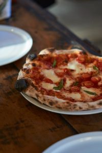 Pizza Margarita con queso fior di latte derretido y albahaca fresca.
