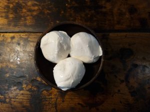 Queso mozzarella fior di latte fresco en un recipiente rústico.